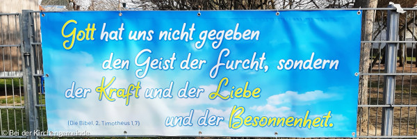 Ein Banner vor dem Zaun der KiTa mit der Aufschrift: "Gott hat uns nicht gegeben den Geist der Furcht, sondern den der Kraft und der Liebe und der Besonnenheit."