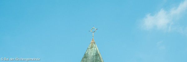 Die Kirchtumspitze unserer Thomaskirche mit Kreuz vor blauem Himmel
